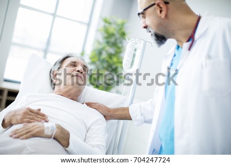 Doctor talking to patient in hospital bed Royalty-Free Stock Photo #704247724