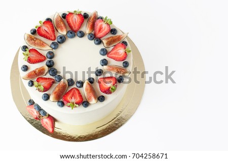 Cake with whipped white cream, decorated with fresh strawberries, blueberries and figs. Picture for a menu or a confectionery catalog. Isolated.