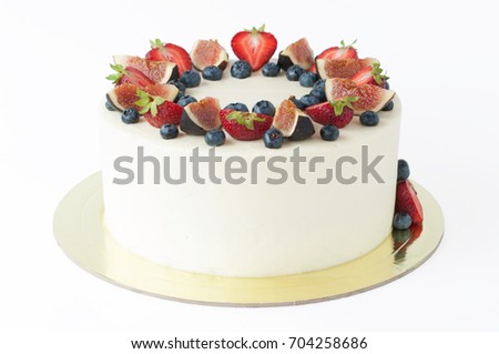 Cake with whipped white cream, decorated with fresh strawberries, blueberries and figs. Picture for a menu or a confectionery catalog. Isolated.