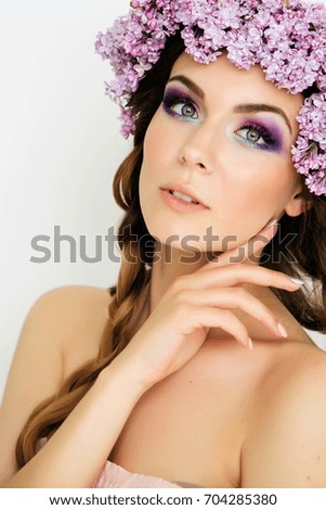 Spring girl with a wreath of flowers. The summer image with a bright make-up. Flowers in the hair. Close-up portrait.