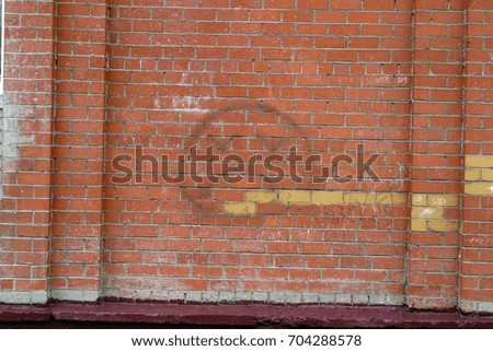 Texture orange brick wall with yellow and red color. Painted a huge sad smiley with closed eyes crosses.