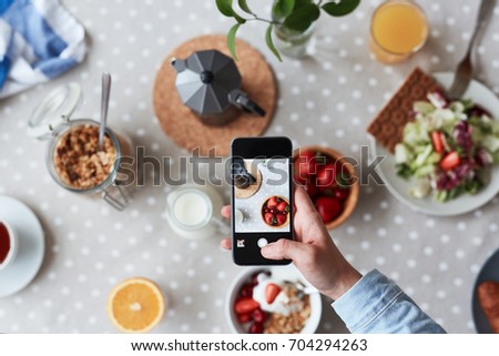 Unrecognizable food blogger taking picture of appetizing breakfast with help of mobile phone, focus on foreground