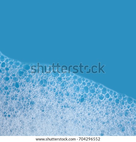 White soap bubbles foam isolated on blue background. Suds shower texture macro view photo