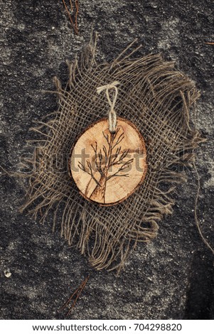 Handmade wooden decoration with the rope lying on the stone.
