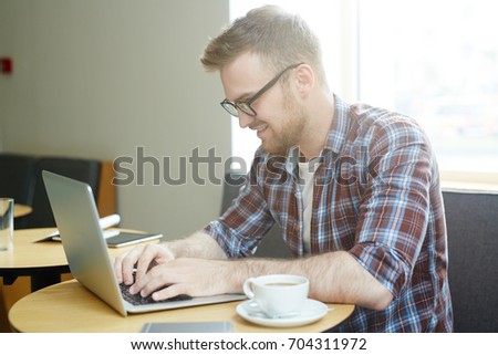 Young mobile man with laptop typing or searching in the net