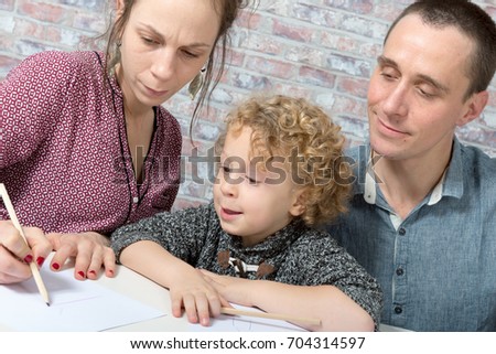 happy young family, blond child, father and mother drawing