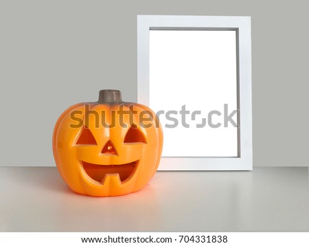 Happy Halloween background. Pumpkin toy smiling face. Plastic Jack o lantern with light. Vertical white photo frame mock up template on the table. Empty space. Trick or treat. Holiday sign symbol.
