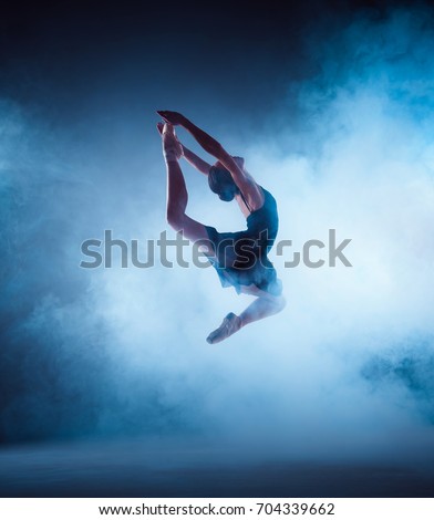 Beautiful young ballet dancer jumping on a lilac background.