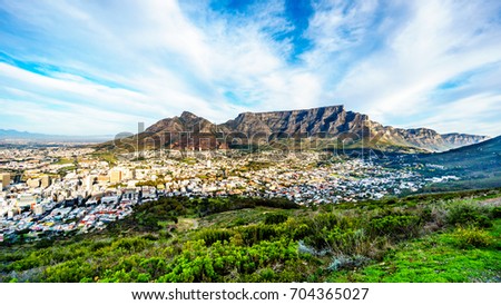 Sun setting over Cape Town, Table Mountain, Devils Peak, Lions Head and the Twelve Apostles. Viewed from the road to Signal Hill at Cape Town, South Africa Royalty-Free Stock Photo #704365027