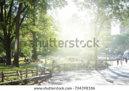 Sunny day in New York City park blurred background scene with sunlight shining on crowds of people