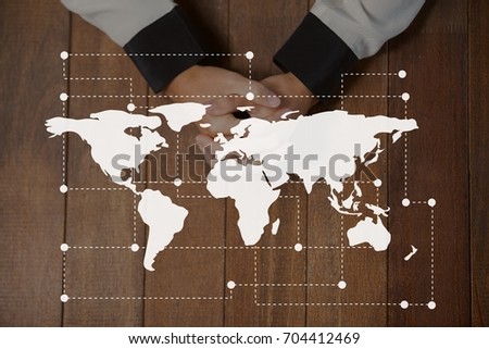 Digital composite of World map icon against hands on a table photo