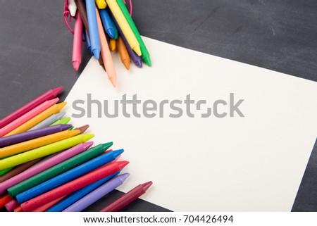 crayons and blank page on the blackboard