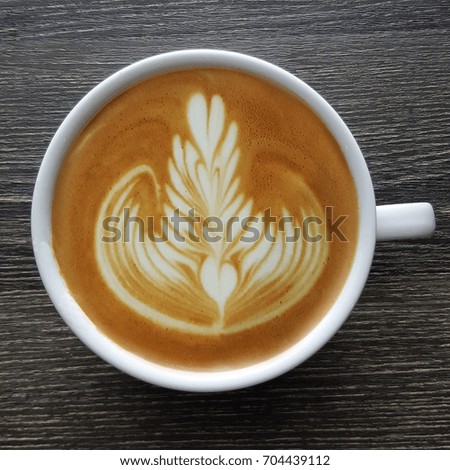 Top view of a mug of latte art coffee on timber background.