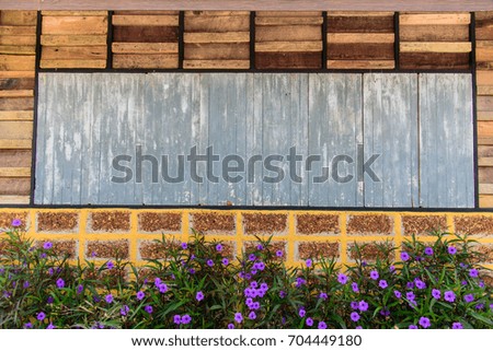 Old wooden plank and brick wall pattern. Antique rough and rustic wall of rural house with flowers.