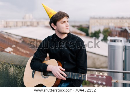 Musician at birthday party. Celebration on roof. Young festive guitarist outdoors