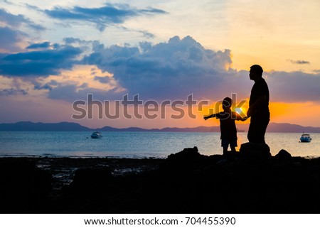 Silhouette image of father and son at the beach before sunset background