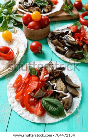 Vegetarian tacos with eggplant, cherry tomatoes, sweet peppers on a bright wooden background. Mexican snack.