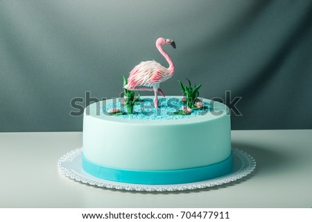 A beautiful cake, decorated with a figure of pink flamingos in the pond. The concept of the Original design of desserts