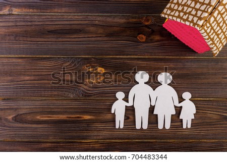 Happy paper family with house on dark vintage wooden background