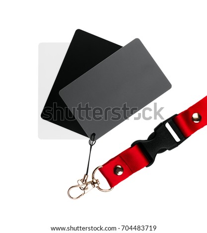 Three cards, one white, one grey and one black, attached together, and on a red strap, on a white surface. isolated on white background