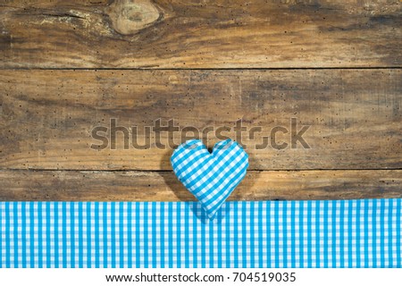 Blue heart and checkered fabric on rustic wooden board with copy space. Background for Bavarian Oktoberfest or Beer garden.