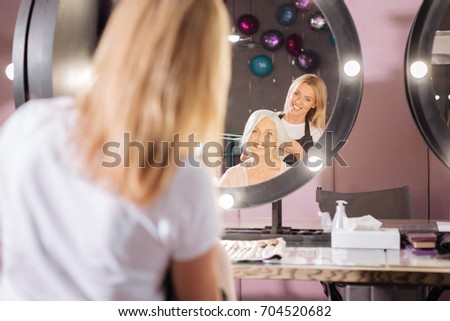 Smiling hairdresser experimenting with clients haircut