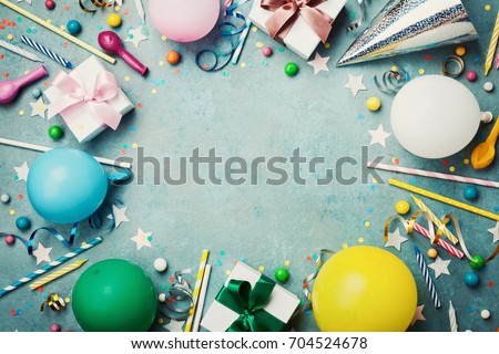 Holiday frame or background with colorful balloon, gift, confetti, silver star, carnival cap, candy and streamer. Flat lay style. Birthday or party greeting card with copy space.