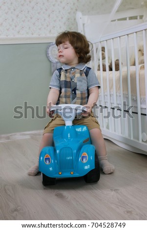 litle boy sit on a toy car