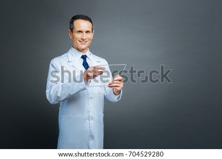 Mature scientist posing with transparent gadget