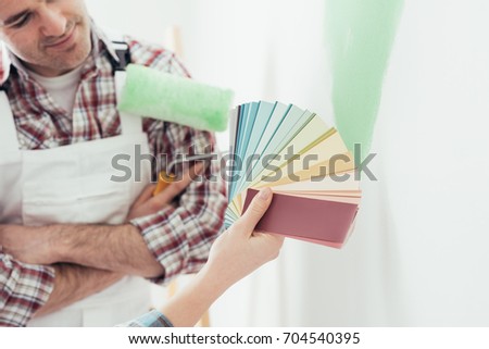 Woman choosing the perfect paint color for her room with a professional painter and decorator, she is holding color swatches