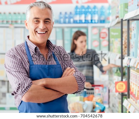 Confident smiling supermarket clerk posing at the shopping mall, retail job concept Royalty-Free Stock Photo #704542678