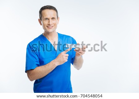 Friendly physician pointing toward pills organizer