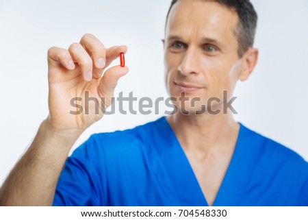 Positive minded doctor looking at red pill
