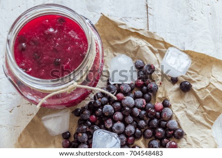 Jelly from black currant and berries on a light wooden background. Autumn preservation. Healthy food.