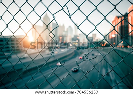 City sunrise skyline through the wire mesh fence. Abstract blurred cityscape background