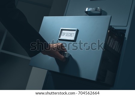 Office worker searching top secret confidential information in the office late at night, data theft and security concept Royalty-Free Stock Photo #704562664
