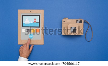 User editing photos on a cardboard tablet and handmade carton camera, crafts and creativity concept