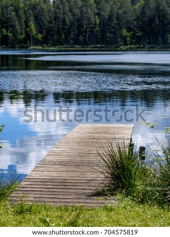 reflection of clouds in the lake with boardwalk and trees in background - vertical, mobile device ready image