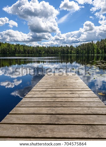 reflection of clouds in the lake with boardwalk and trees in background - vertical, mobile device ready image