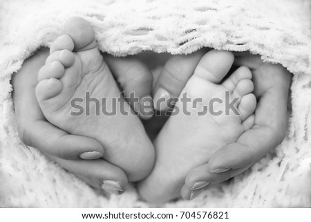 the legs of the child in mothers hands black and white photo