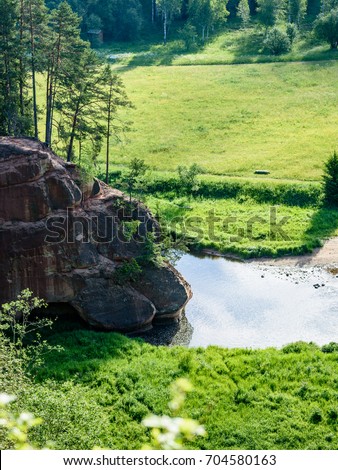 beautyful morning light over forest river of Amata, Cesis, Latvia. sandstone cliffs and green vegetation around water in summer - vertical, mobile device ready image