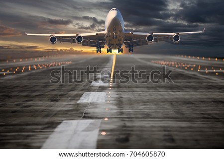 Passenger aircraft takes off from the airport runway. The plane is climbing into the sunset sky. Royalty-Free Stock Photo #704605870