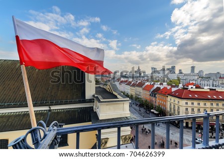 Poland Flag in Blue Sky and the centre of Warsaw in background Royalty-Free Stock Photo #704626399