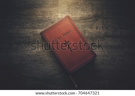 Glow illuminating the Holy Bible in the dark. Royalty-Free Stock Photo #704647321