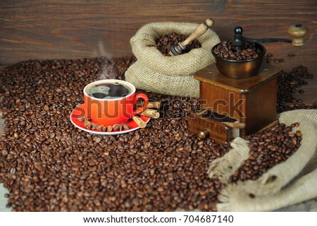 Coffee, cappuccino or espresso smoke and cinnamon sticks on a wooden table with a coffee grinder
