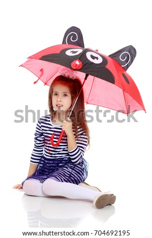 Beautiful little girl long hair and white bow on her head , in a summer dress in stripes.She's sitting on the floor hiding under the umbrella.Isolated on white background.