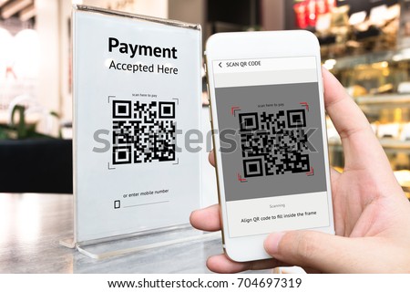 Qr code payment , online shopping , cashless technology concept. Coffee shop accepted digital pay without money , plastic tag on table and hand using mobile phone application to scan qr code. Royalty-Free Stock Photo #704697319