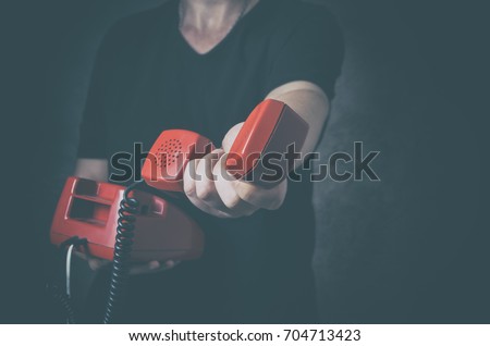 Sos phone or helpline for people in personal crisis - unrecognizable man with old red phone in hand Royalty-Free Stock Photo #704713423