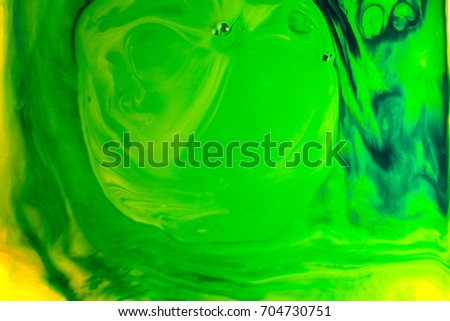 Yellow and green oil paint on water abstract background.