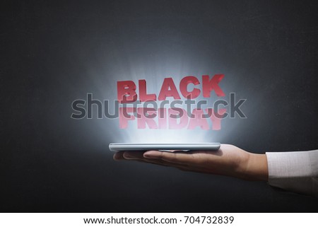 People holding tablet and showing Black Friday advert over black background